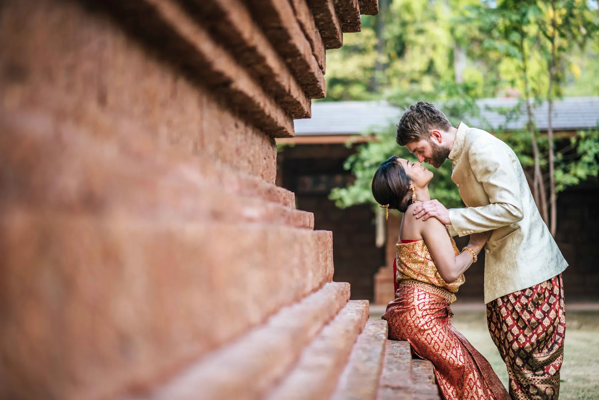A couple sharing a quiet moment beside a traditional Kerala building